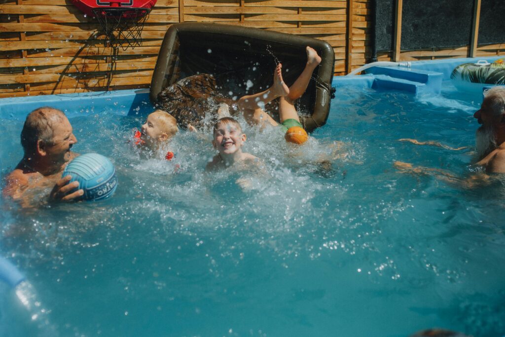 A few kids play games with older adults in a swimming pool.